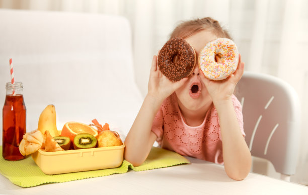 快乐美丽的小女孩正在吃甜甜圈图片下载