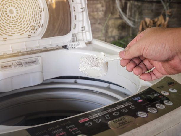 往洗衣机里倒洗衣粉或洗衣粉的人。图片下载