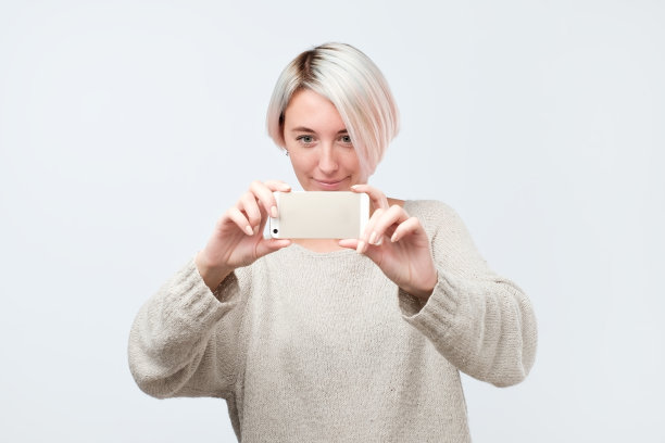 年轻的欧洲妇女在毛衣使照片使用电话图片下载