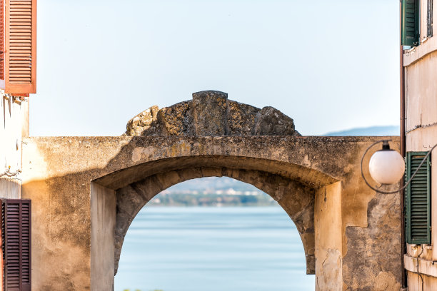 Castiglione del Lago，意大利翁布里亚小镇村庄的小巷街道，在阳光明媚的夏天，拱门入口框架湖水图片下载