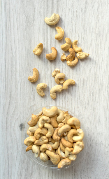 健康的食物背景图片特写腰果。坚果纹理在白色灰色的桌子上的杯子盘上的视图图片下载