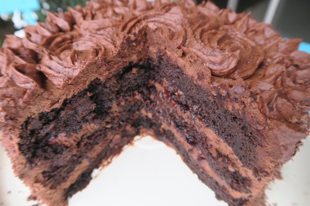 近距离的巧克力生日蛋糕/海绵蛋糕/黑森林蛋糕照片与管道甘纳许糖霜奶油奶油玫瑰和鲜花图片下载