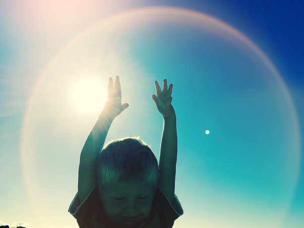 孩子的手在空中与太阳和电晕效应背后图片下载