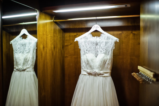 白色的婚纱挂在木质的衣橱里。图片下载