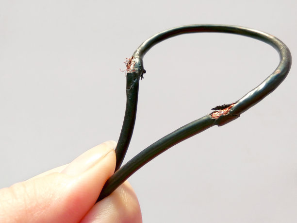 白色背景上损坏的黑色电线。危险破损电缆图片下载