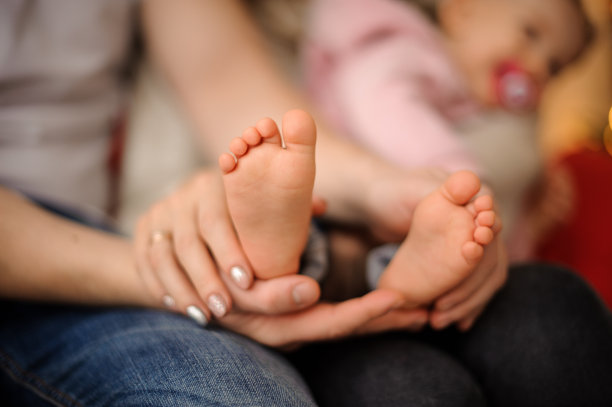 一个女人用手牵着她可爱的小女儿的脚图片下载