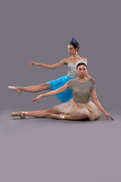 严肃的芭蕾舞演员坐着，而女搭档在后面摆姿势图片下载