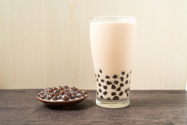 一杯珍珠奶茶(也叫珍珠奶茶)和一盘在木制背景上的木薯球。珍珠奶茶是台湾最具代表性的饮品。台湾的食物。与复制空间。素材图片