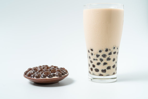 一杯珍珠奶茶(也叫珍珠奶茶)和一盘在白色背景上的木薯球。珍珠奶茶是台湾最具代表性的饮品。台湾的食物。与复制空间。素材图片