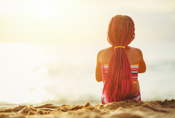 快乐的孩子女孩穿着泳衣坐在海滩上日落图片下载