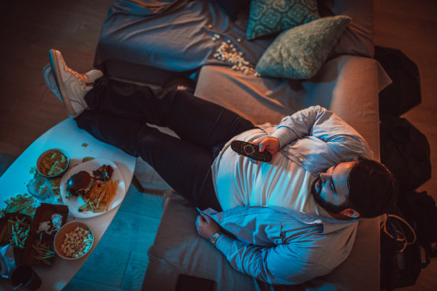 胖男人在家里的沙发上看电视图片下载