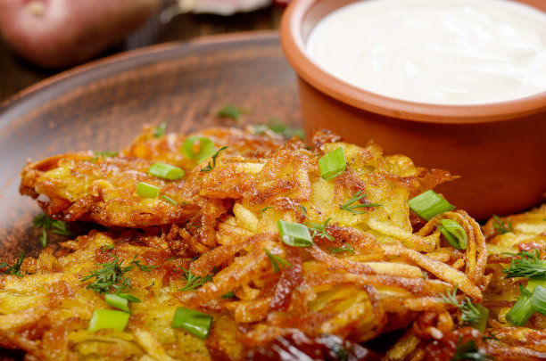 新鲜的自制土豆煎饼与绿色蔬菜和酸奶油的特写照片图片下载