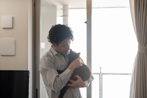 一个男人在窗边抱着一只猫图片下载