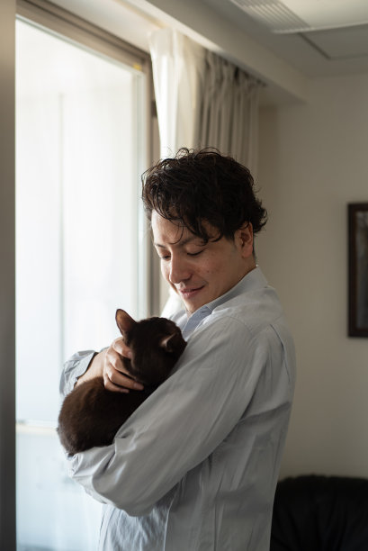 一个男人在窗边抱着一只猫图片下载