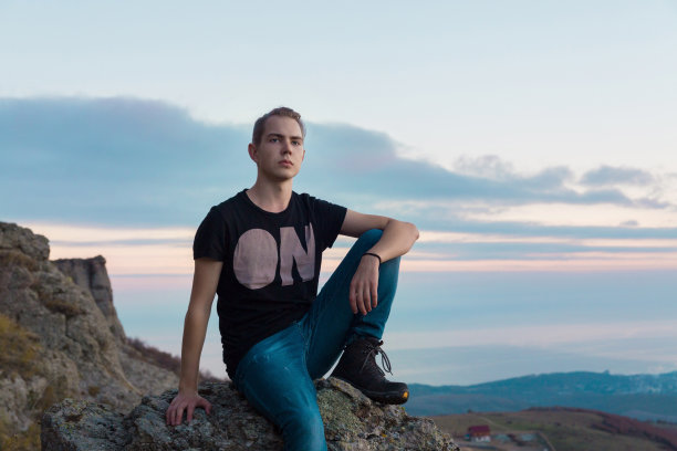 年轻英俊的男子站在山顶上，背景是蓝色和粉红色的夕阳，图片下载