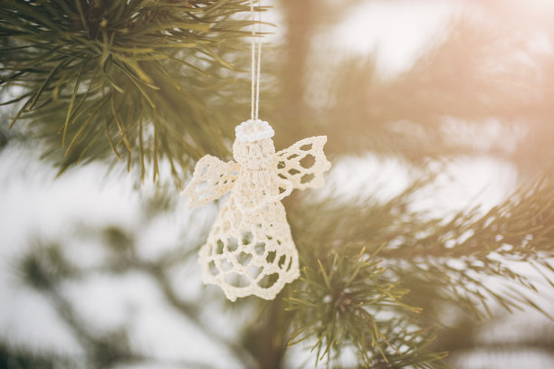 手工天使挂在圣诞树上。冰冻森林中的自然照片。节日快乐装饰明信片。下雪的天气。图片下载