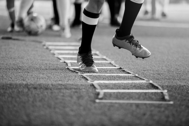 小男孩足球运动员的黑白照片慢跑和跳跃之间的梯子训练足球训练图片下载