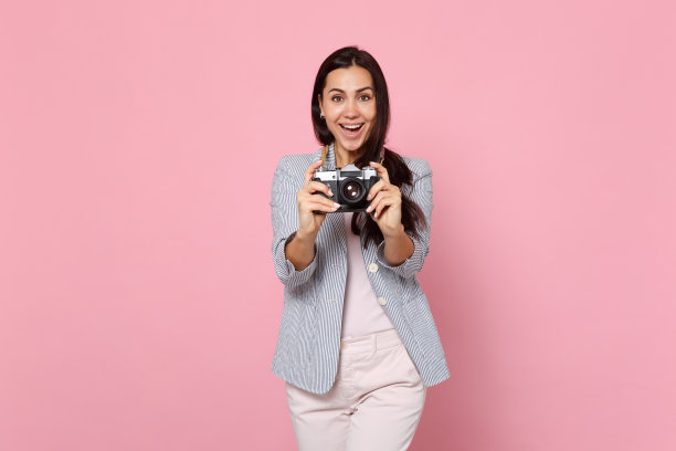 欢快的年轻女子的肖像在条纹夹克拍摄照片上的复古相机孤立在粉色柔和的墙壁背景。人真诚情感生活理念。模拟拷贝空间。图片下载