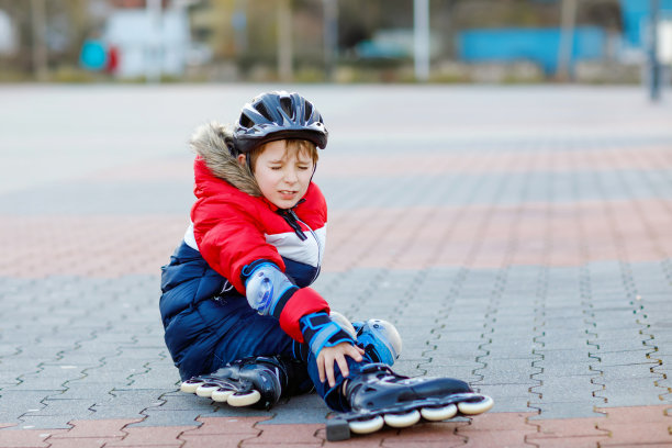 一个小男孩在城里滑旱冰。儿童穿着安全防护服。积极的学生使运动和学习滑冰直排轮滑。摔倒受伤图片下载