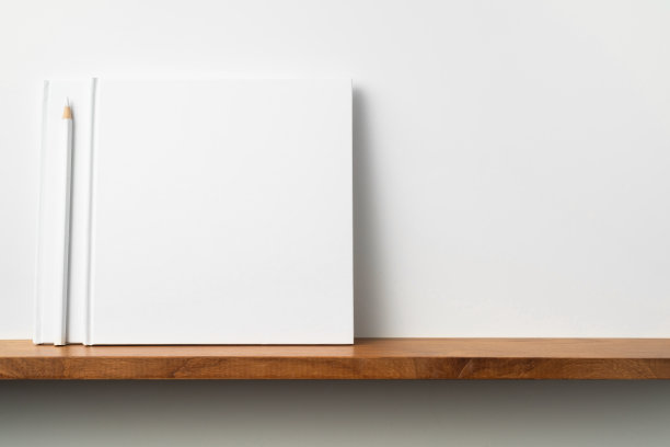白色的方形笔记本放在书架和白色的墙壁上图片下载