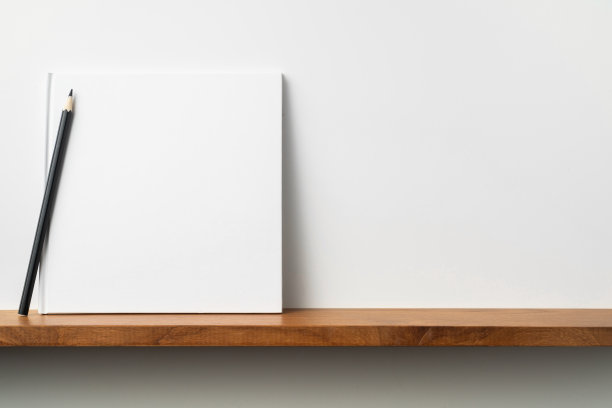 白色的方形笔记本放在书架和白色的墙壁上图片下载