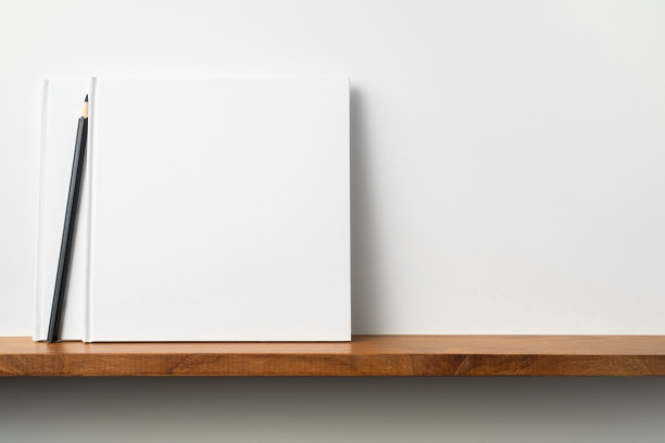 白色的方形笔记本放在书架和白色的墙壁上图片下载
