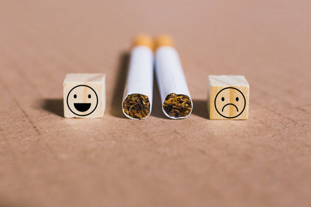 特写的两支香烟和反馈的脸显示积极和消极的情绪上的木头立方体图片下载
