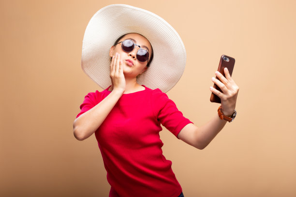 戴着帽子和太阳镜的女人使用智能手机孤立的背景图片下载