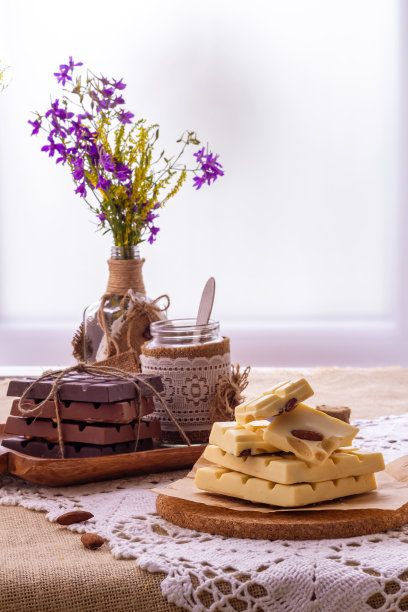 静物画有黑色、乳白色和白色的巧克力棒，盘子和野花的花束背对着窗户。本空间图片下载