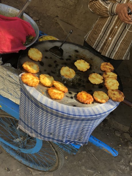 一个男人正在做Aloo tikki / Aloo tikki chaat，在一个大平底锅上用热油油炸，印度街头小吃小贩，印度街头小吃摊，不健康的饮食，新德里，印度，德里肚图片下载
