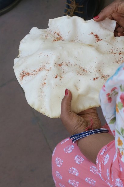 印度妇女拿着从街头小贩那里买来的纸、爆米花、米饼，上面撒着黑盐和红辣椒粉，这是不卫生的食物照片，德里肚，印度图片下载
