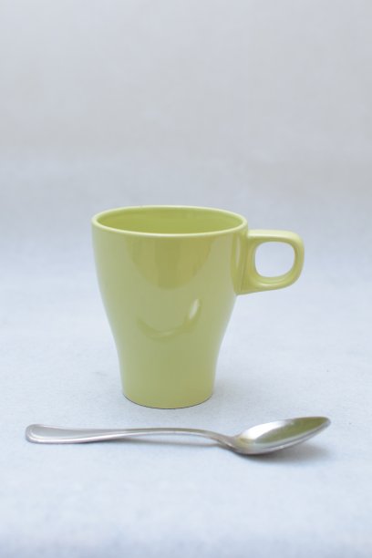 黄绿色陶瓷马克杯和不锈钢勺图片下载