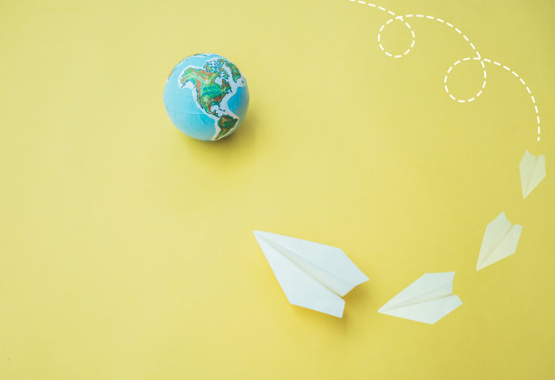 纸飞机与地球仪在黄色的纸背景。图片下载