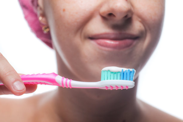 一个用毛巾顶着头刷牙的漂亮女人。早上的治疗方法图片下载