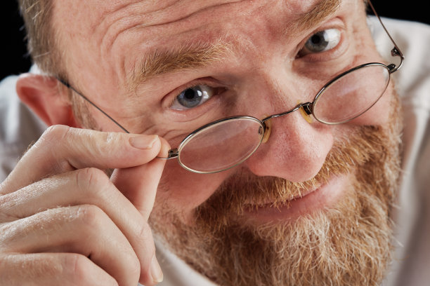 微笑的成熟男子看着他的眼镜在相机图片下载