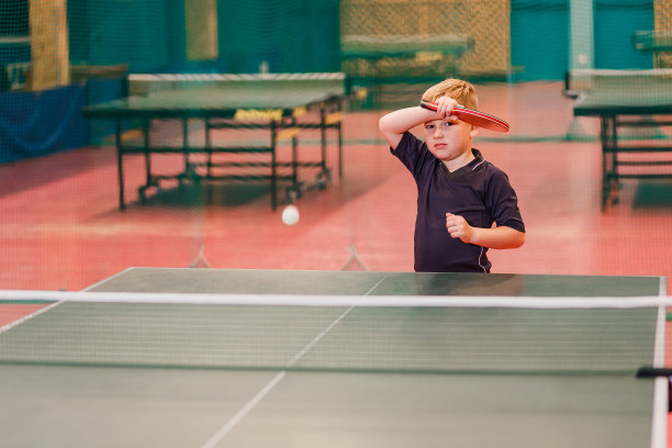 一个男孩在网球馆里打乒乓球图片下载