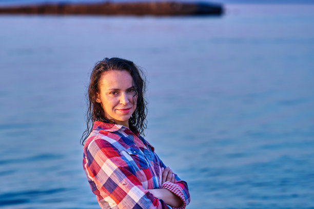 一个黑发湿漉漉的中年妇女的肖像在一个夏天的傍晚在夕阳下的格子衬衫。图片下载