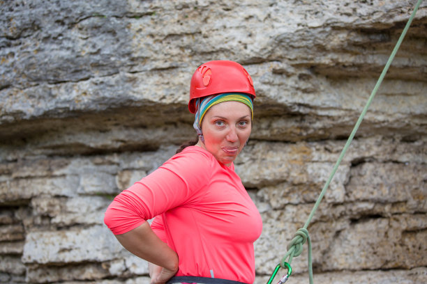 这是一名女性登山者的照片，她的舌头站在山旁边，背景是绿色的景观图片下载