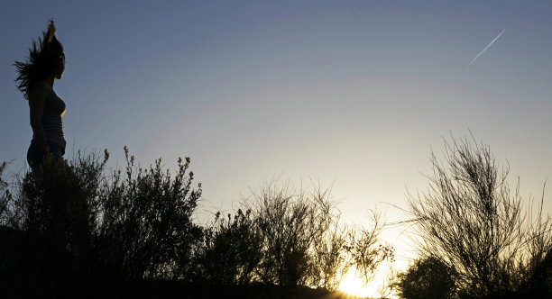 女人的剪影沿着山的边缘走着图片下载