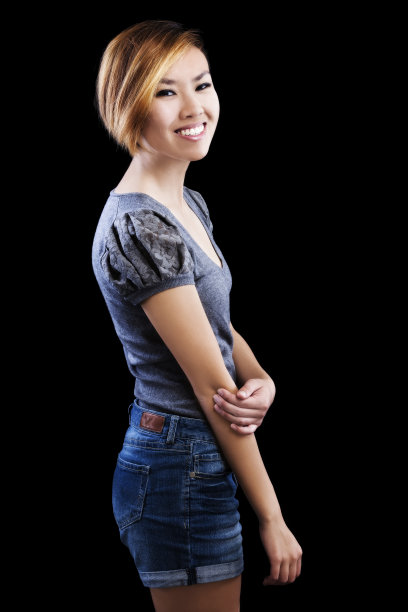 微笑苗条的亚裔美国妇女在牛仔短裤和毛衣图片下载