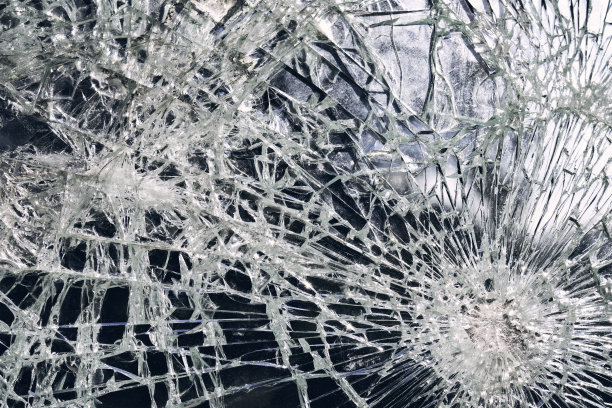 公交车站发生犯罪事件。射击手枪。城市公交车站的玻璃上有洞和裂缝。蓝色天空映衬着破碎的玻璃纹理。有弹孔的破碎玻璃。破坏公物图片下载