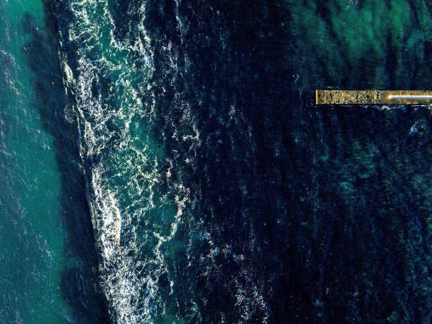 鸟瞰图从无人机到绿松石色的水和石鼹鼠在大海清澈的水与泡沫波。前视图。副本的空间。图片下载