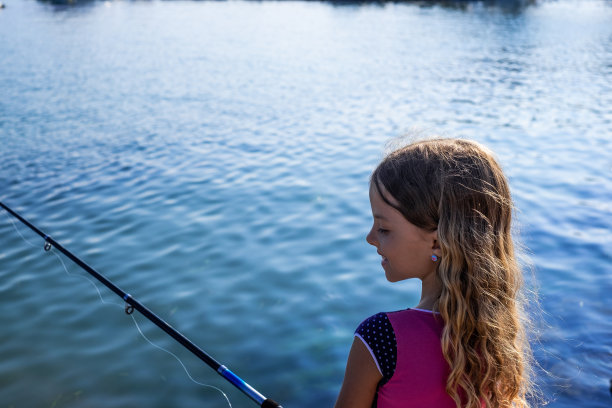侧视图可爱的女孩在海滩钓鱼图片下载