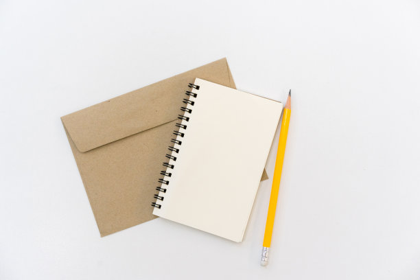 在白色的桌子上，用黄色的铅笔在棕色的字母上用空白的记事本，写下概念图片下载
