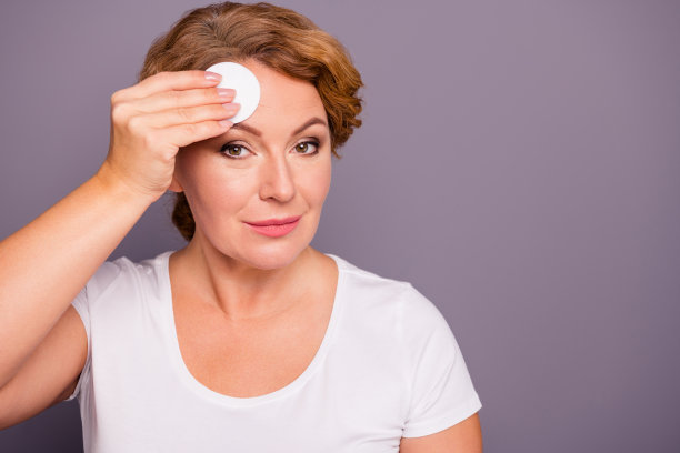 特写照片美丽惊人成熟的她她的女士程序淋浴浴室卸妆检查测试手表皮肤状况用棉垫穿白色t恤孤立的灰色背景图片下载