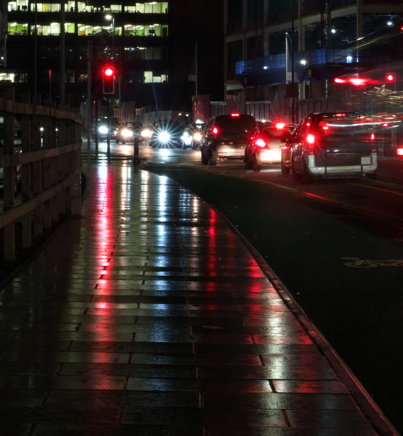 城市场景与交通在城市街道上的运动模糊从移动的汽车和前灯反射在英国利兹潮湿的人行道上图片下载