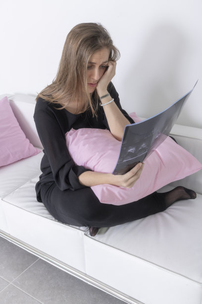 年轻女子坐在白色沙发上看x光片图片下载