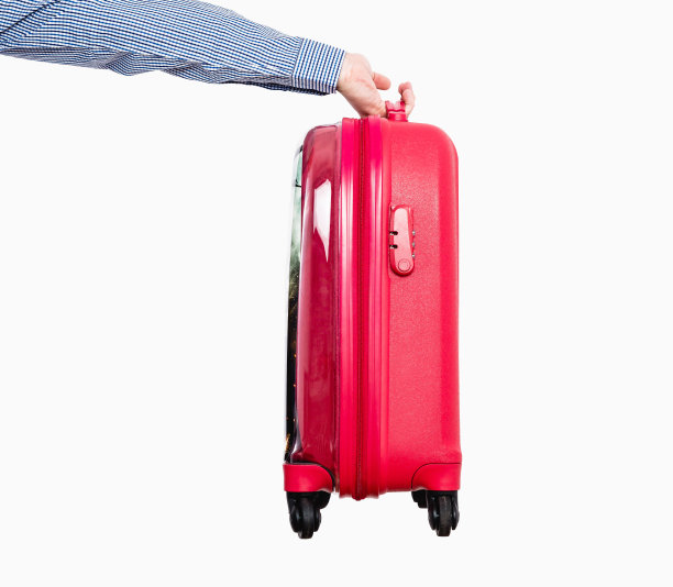 这名男子正在用手递一个带轮子的红色旅行箱，孤立在白色的背景上。图片下载