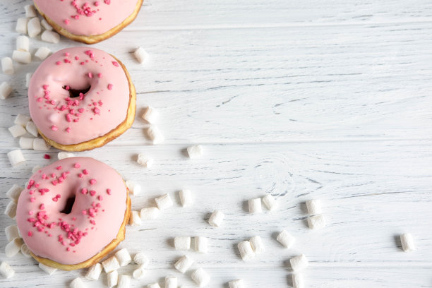 白色背景上的粉色甜甜圈照片。框架文本与甜甜圈和糖果。基础与甜甜圈横幅。社交网络，商店，咖啡馆的甜甜圈横幅图片下载