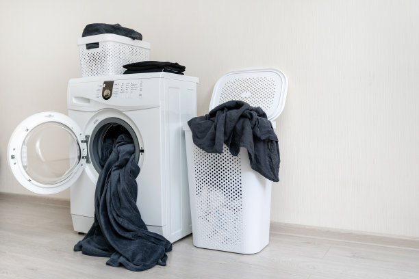 侧面照片的现代洗衣机和两个洗衣篮与纺织品站在明亮的灯光平坦的内部图片下载